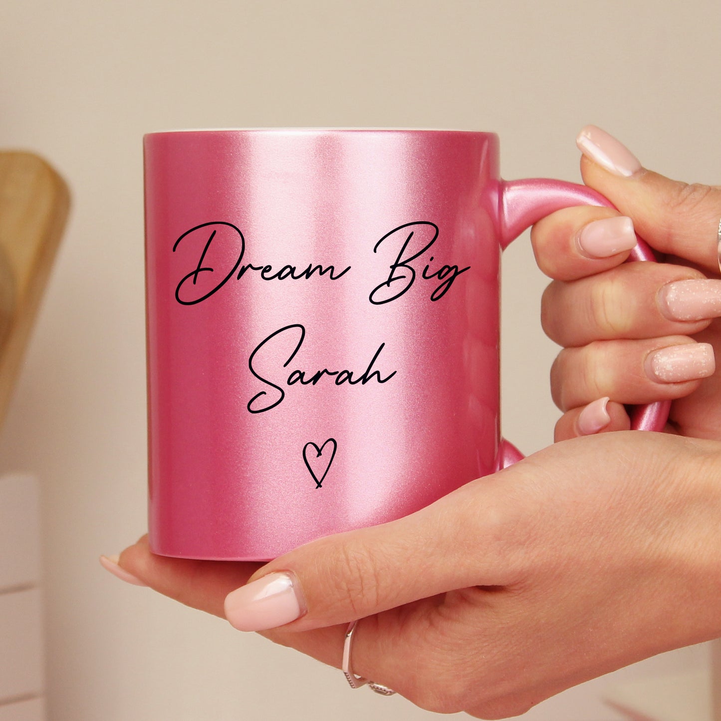Pink glitter mug with personalised graduation details. Shown in someone's hands.