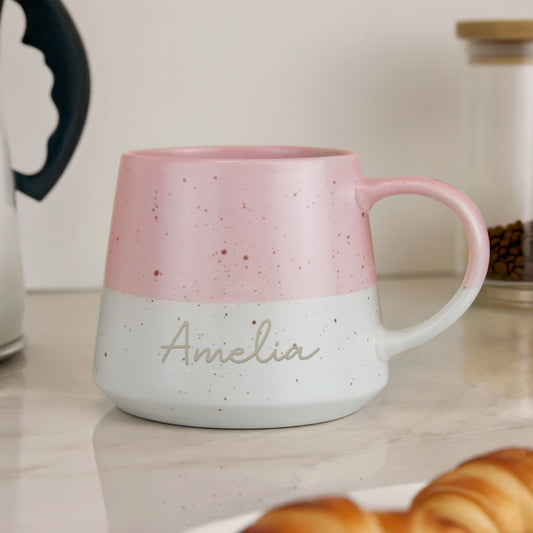 Personalised pink and white speckled mug with 'Amelia' on a kitchen counter