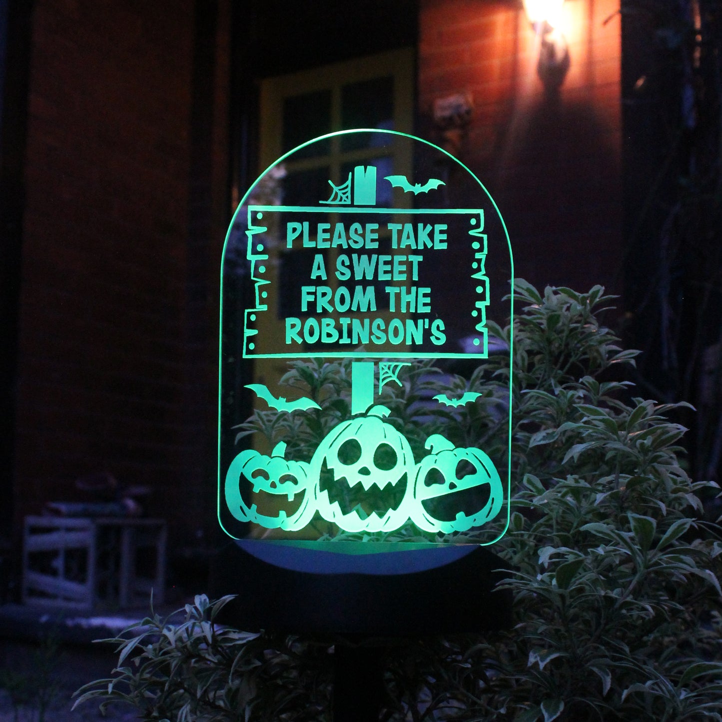 Halloween-themed decorative sign with pumpkins and text 'Please take a sweet from the Robinsons' glowing in the dark.