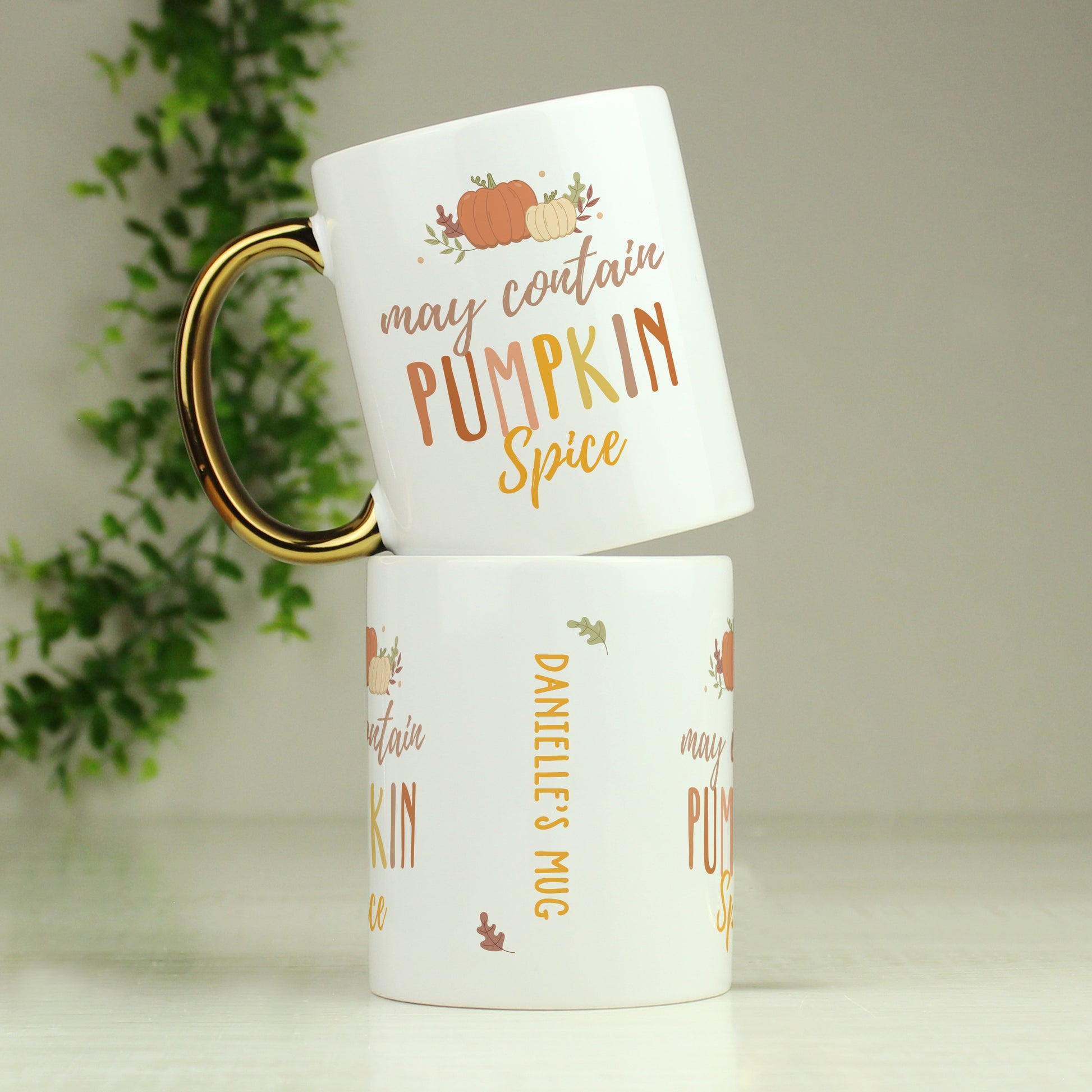 Two white mugs with pumpkin spice design and text on a light background