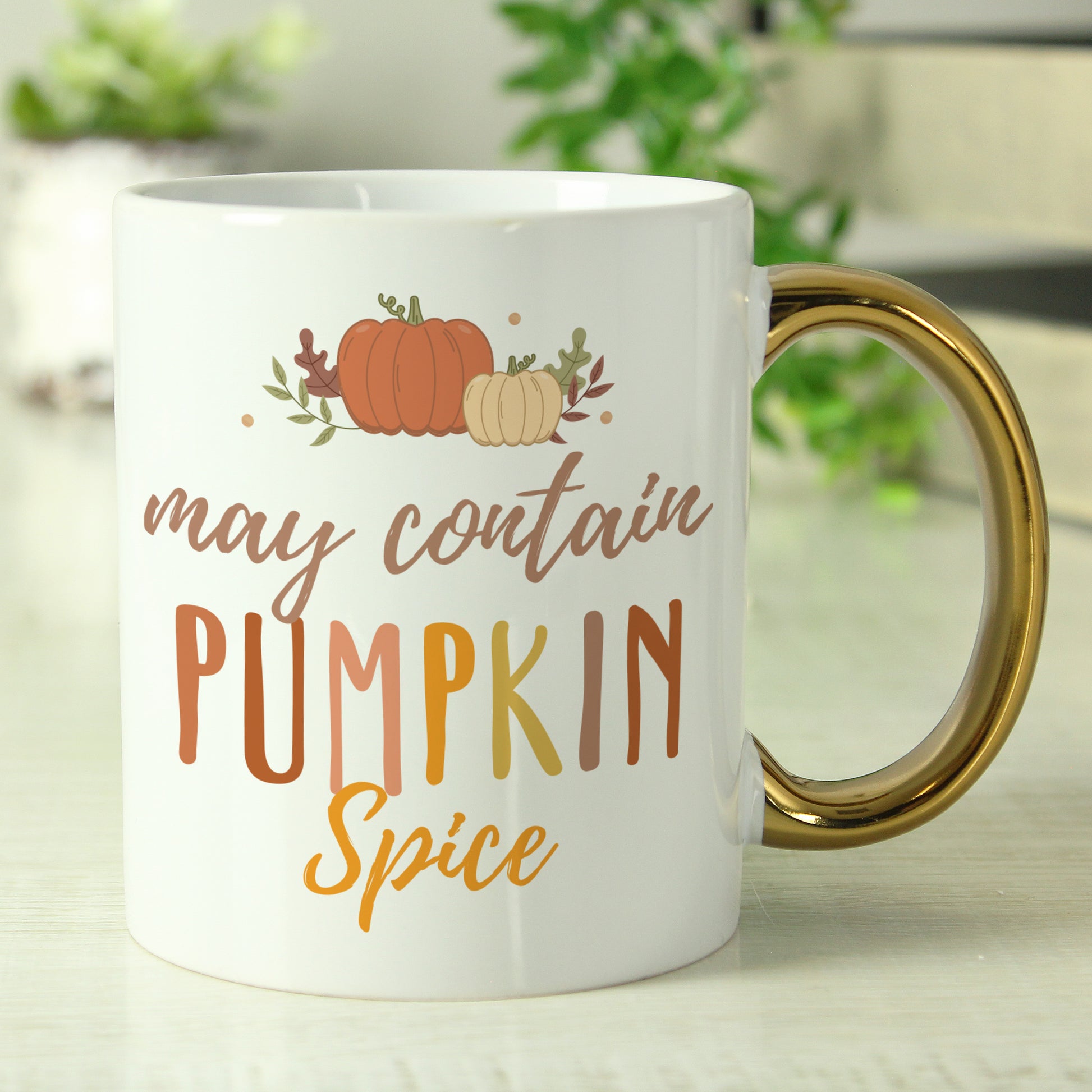 White mug with 'may contain pumpkin spice' text and pumpkins on a light background