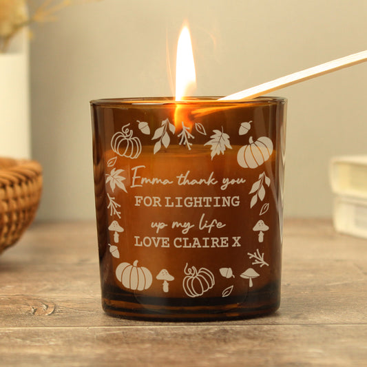 Amber glass candle holder with engraved text and illustrations on a wooden surface