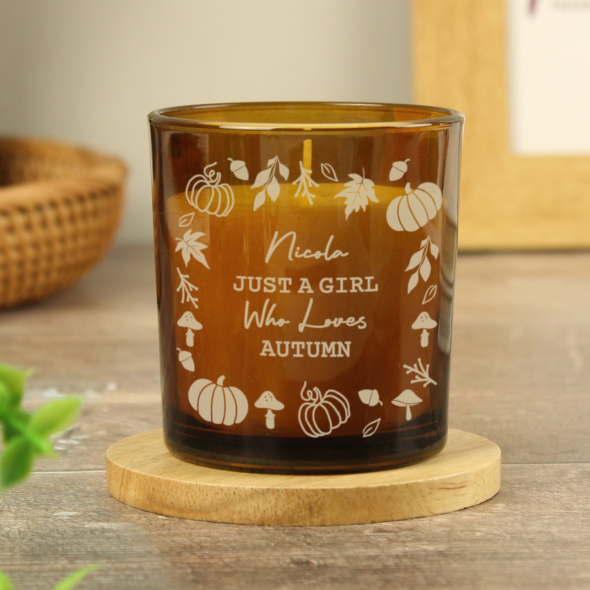 Amber candle holder with Halloween-themed design and text on a wooden coaster.