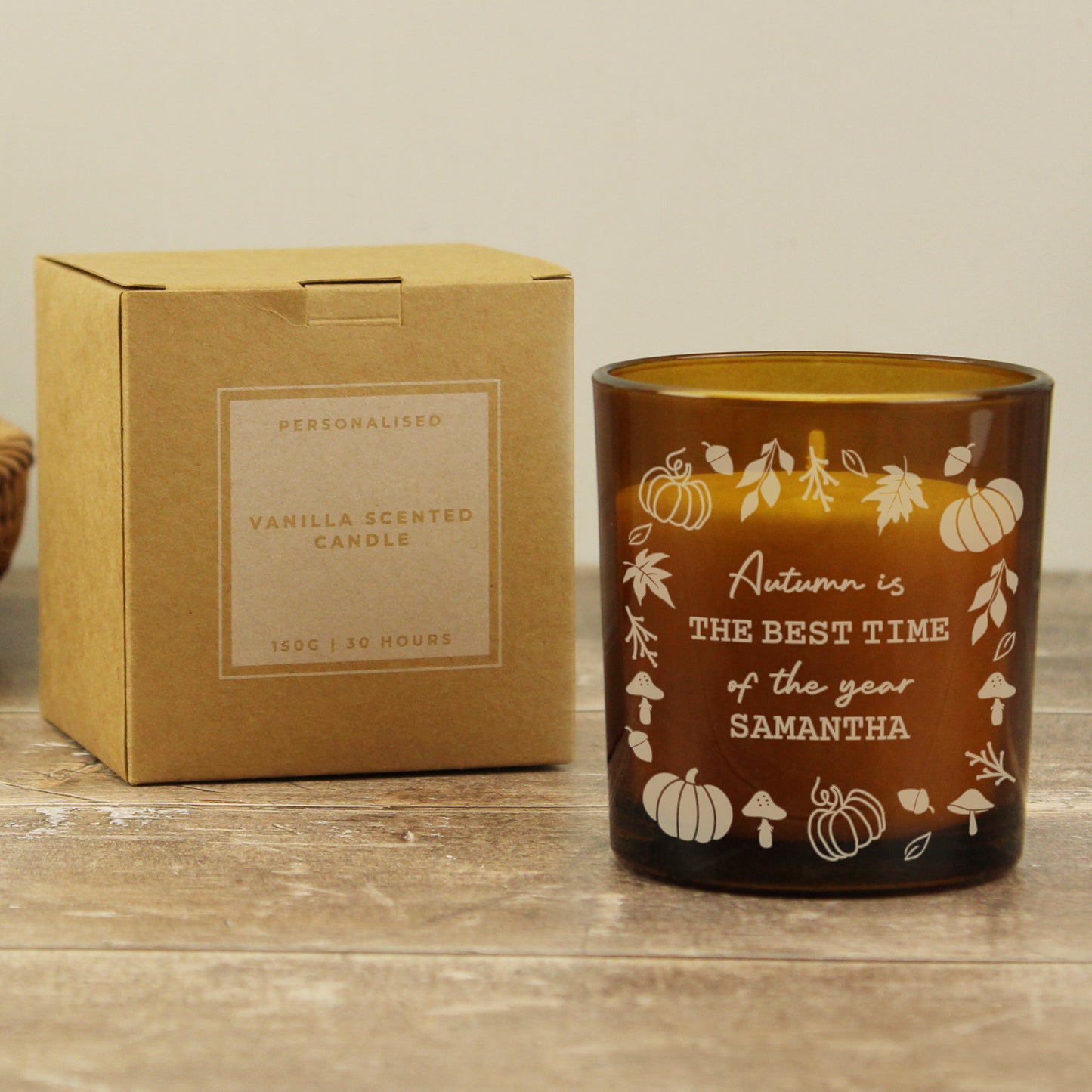 Personalised Halloween-themed candle with decorative text and pumpkins, next to its cardboard box on a wooden surface.