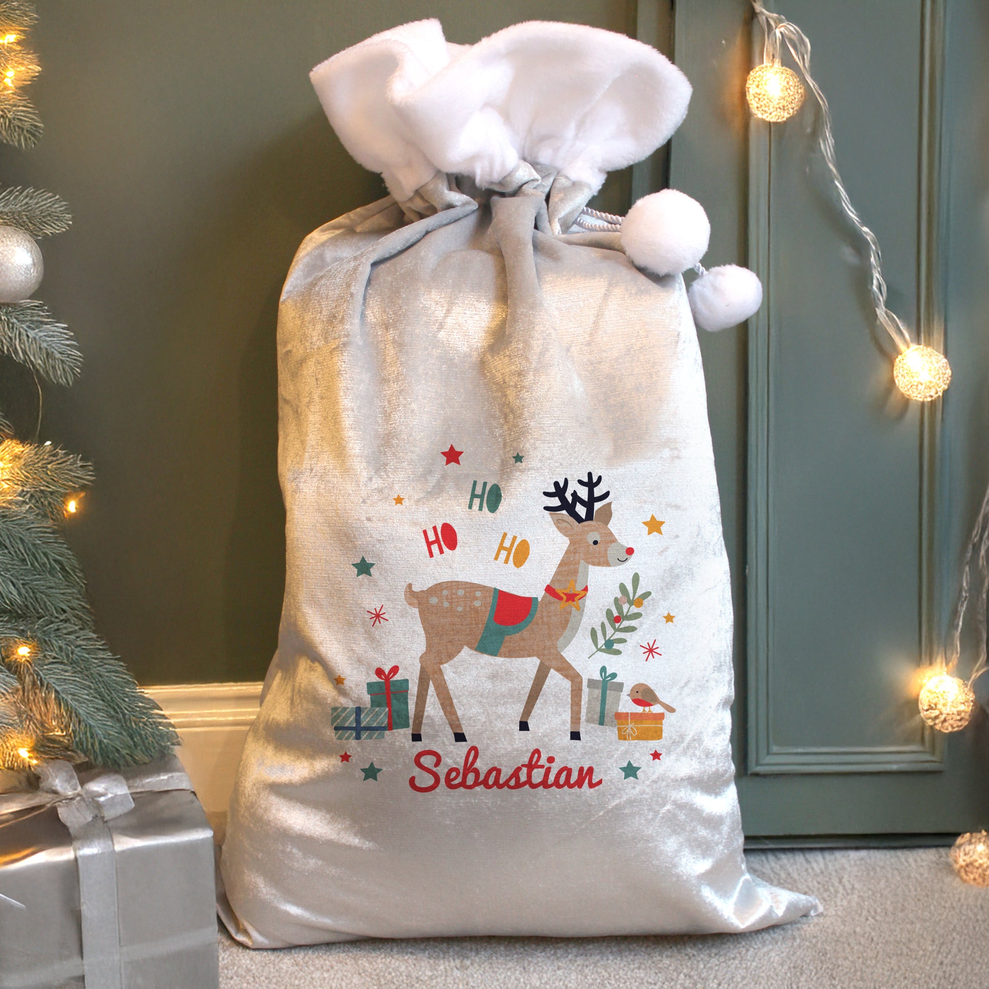 White fleece Santa Sack with reindeer image and Sebastian text, by the tree.