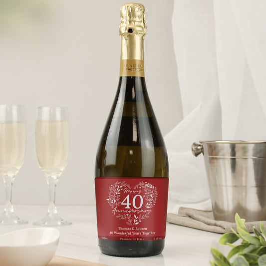 Bottle of champagne with a personalised label on a table with glasses and a bucket.
