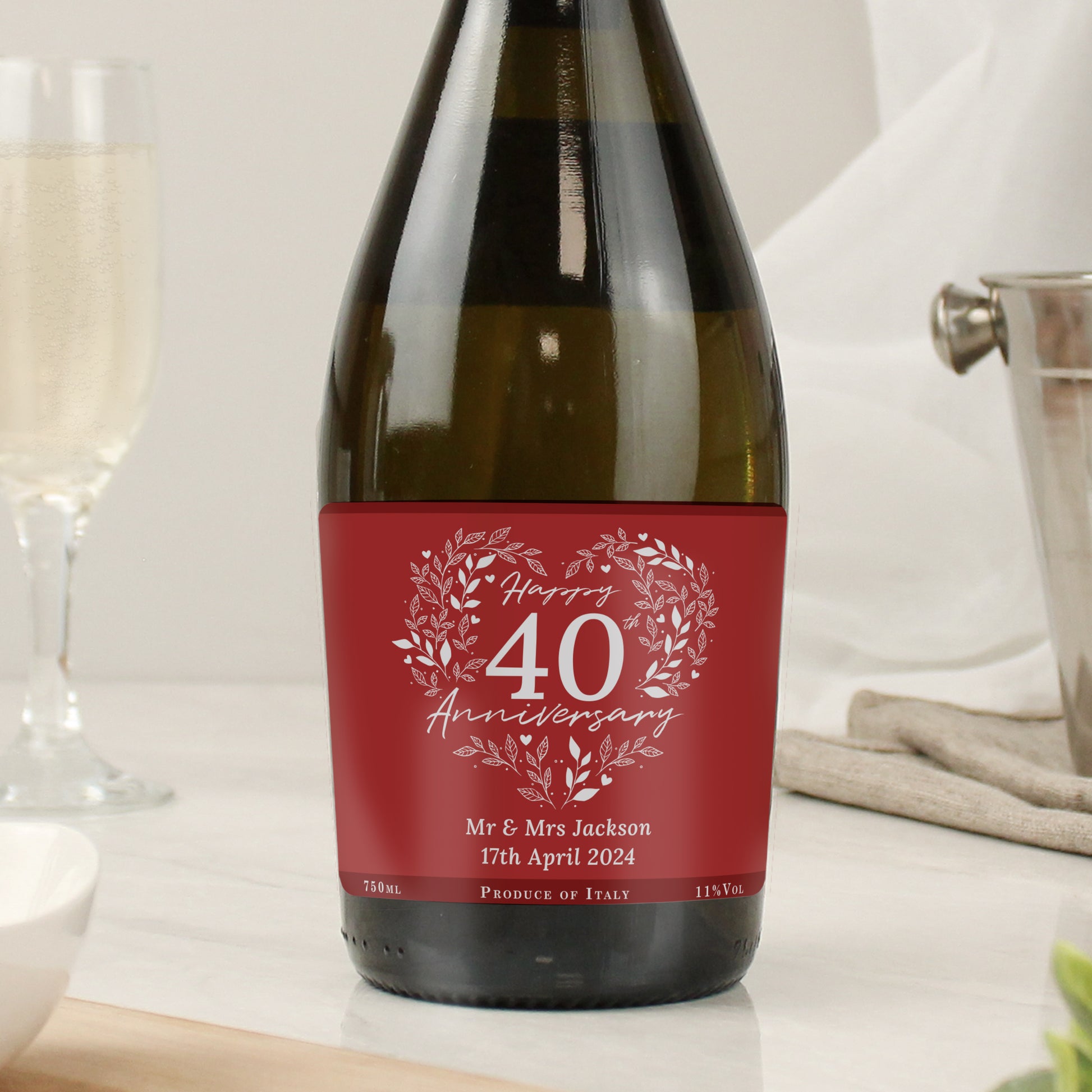 Wine bottle with a red anniversary label on a table with glasses.