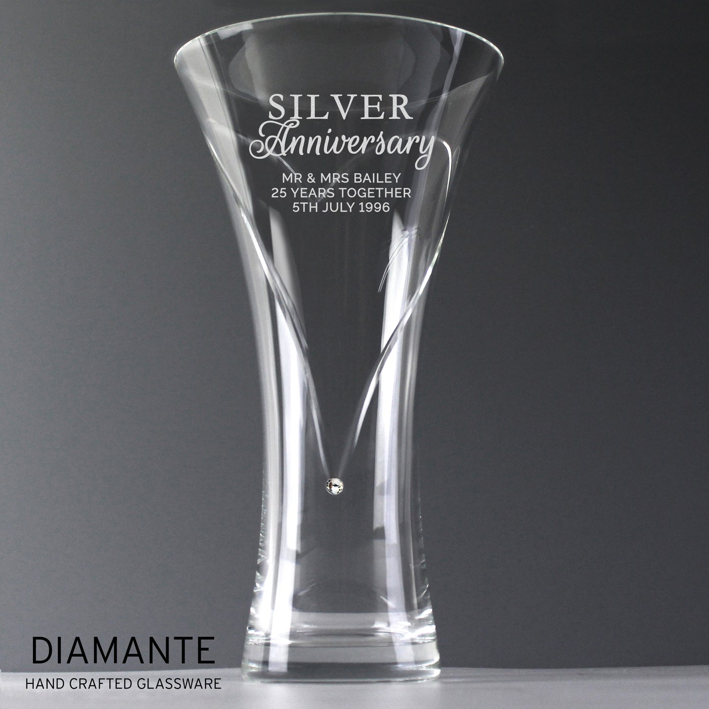 Clear glass vase with engraved 'Silver Anniversary' text on a dark background