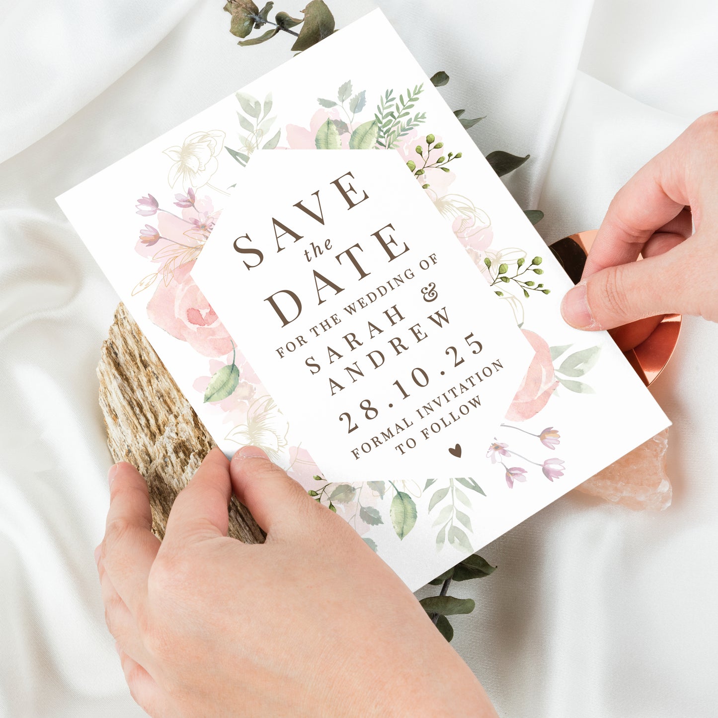 Save the date card with floral design held by hands on a light background