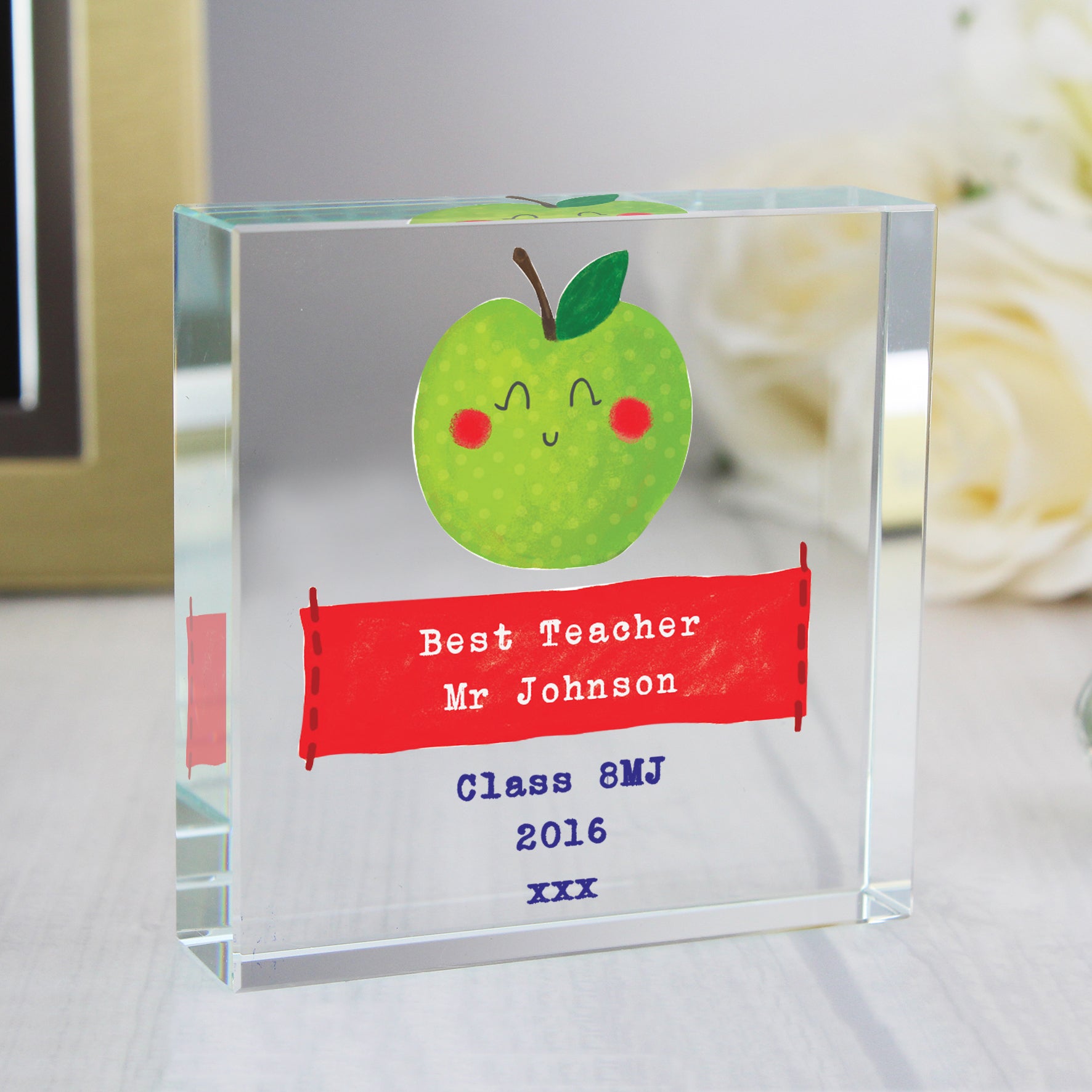 Clear glass block with a cartoon apple and personalised text on a light surface.
