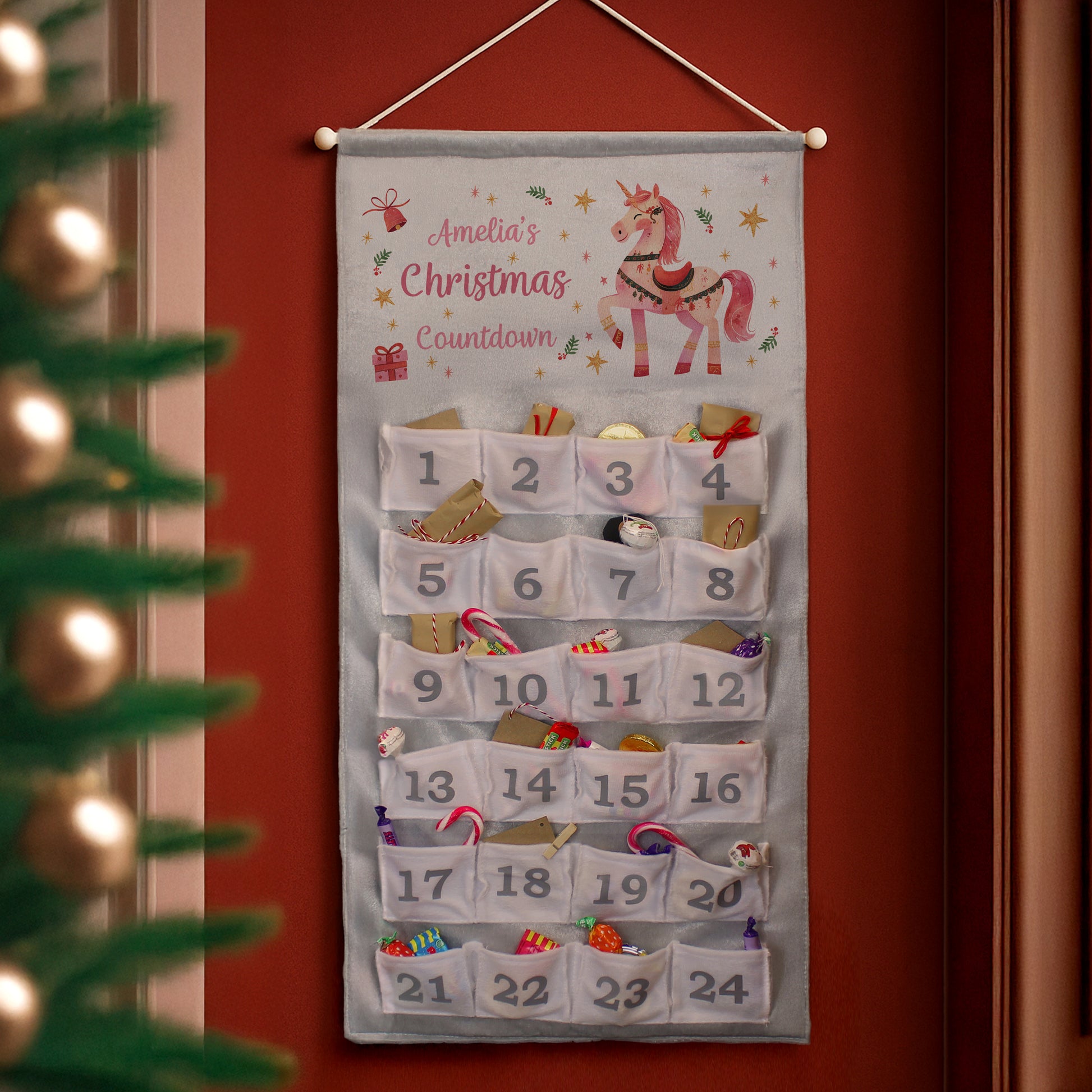 Hanging Christmas advent calendar on a red wall. Personalised text - Amelia's Christmas Countdown.