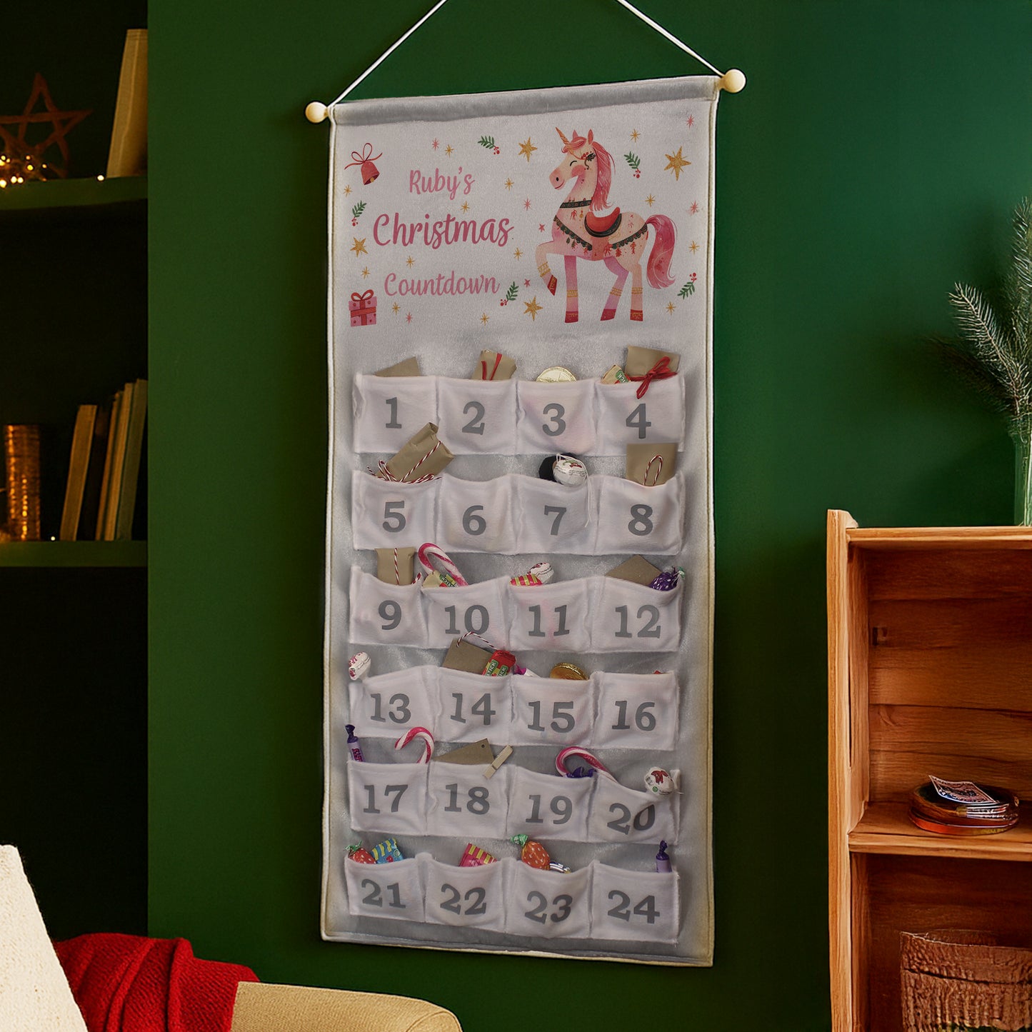 Christmas countdown calendar with a unicorn design on a green wall.