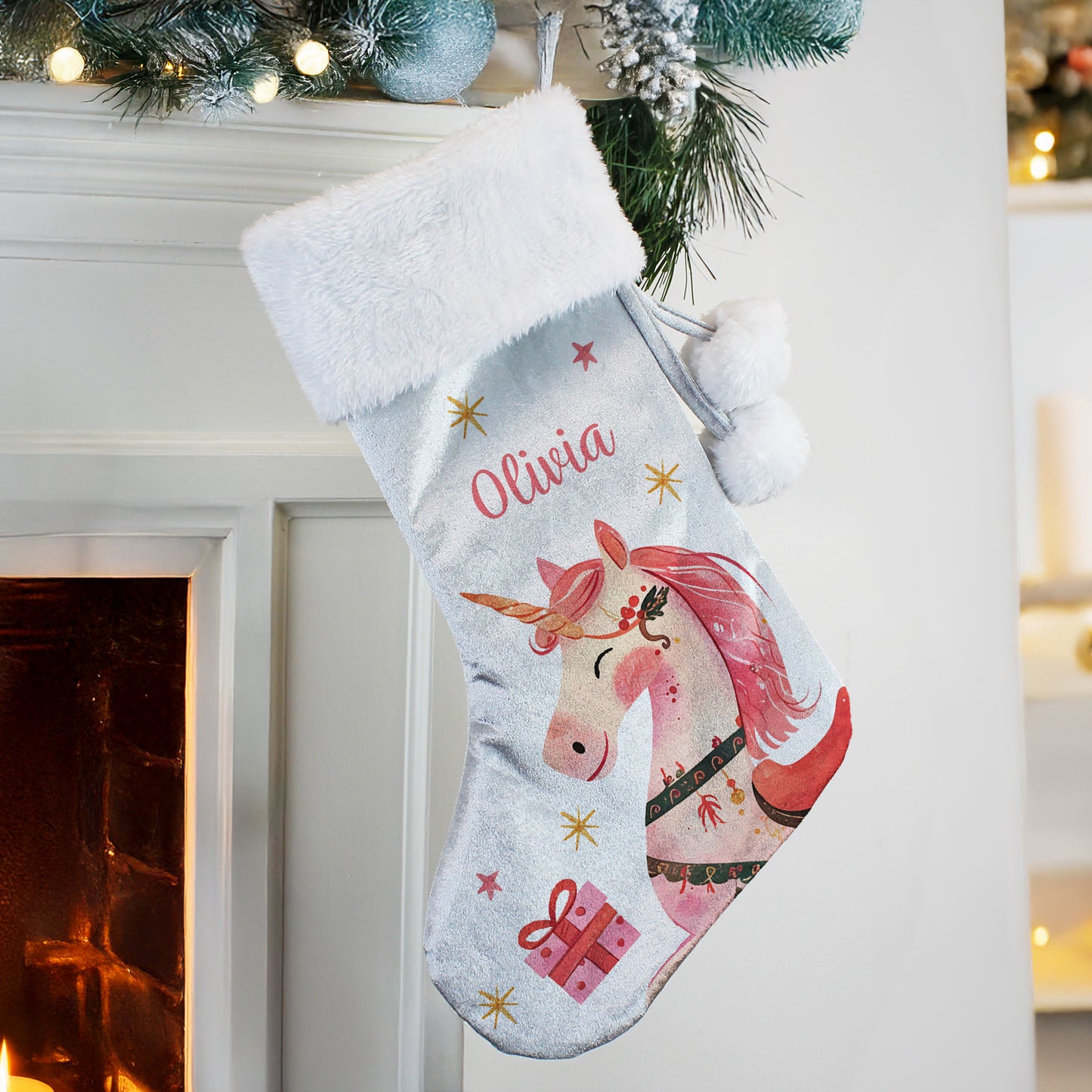 Personalised unicorn Christmas stocking with 'Olivia' on a fireplace mantel.