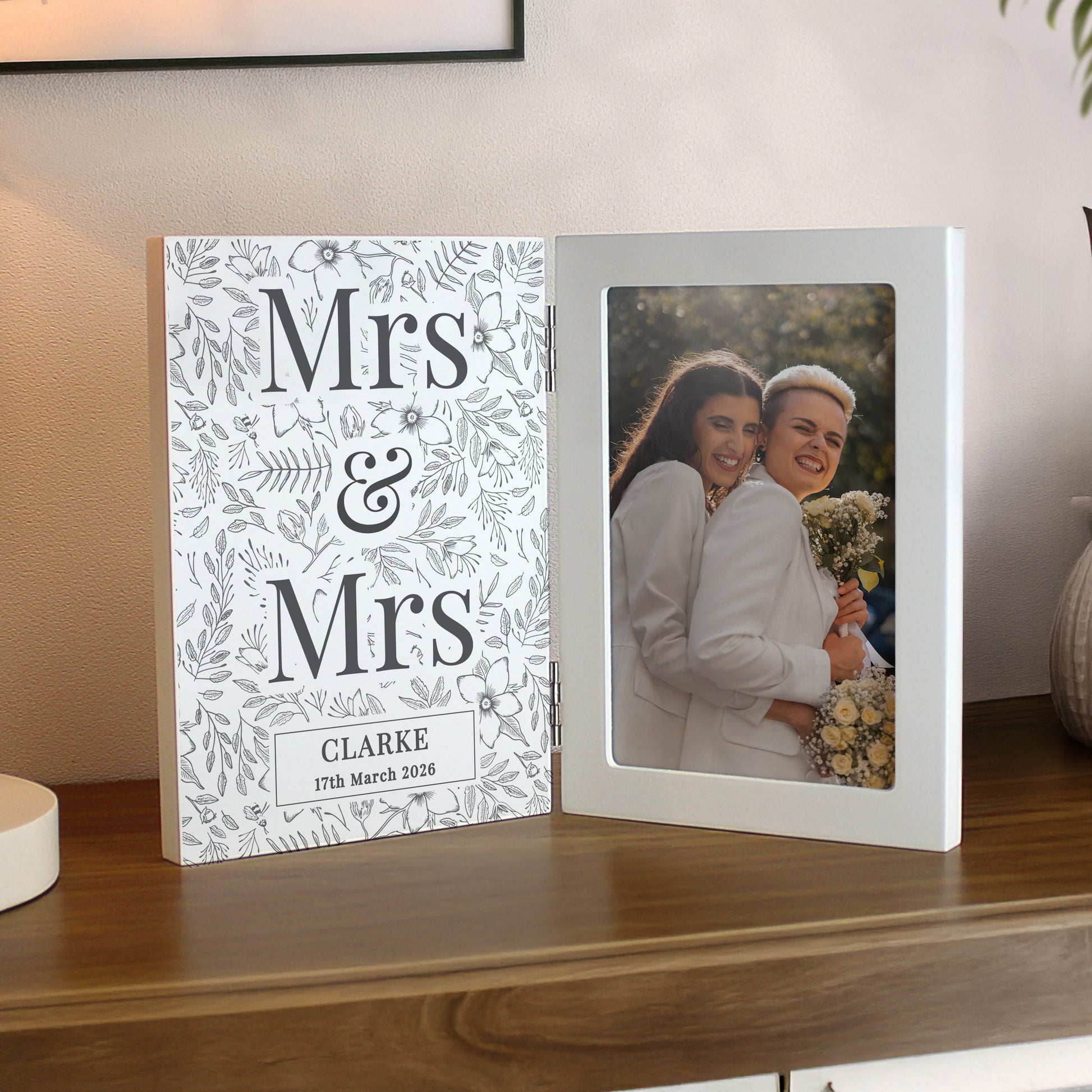 Personalised photo album with 'Mrs & Mrs' design on a wooden surface.