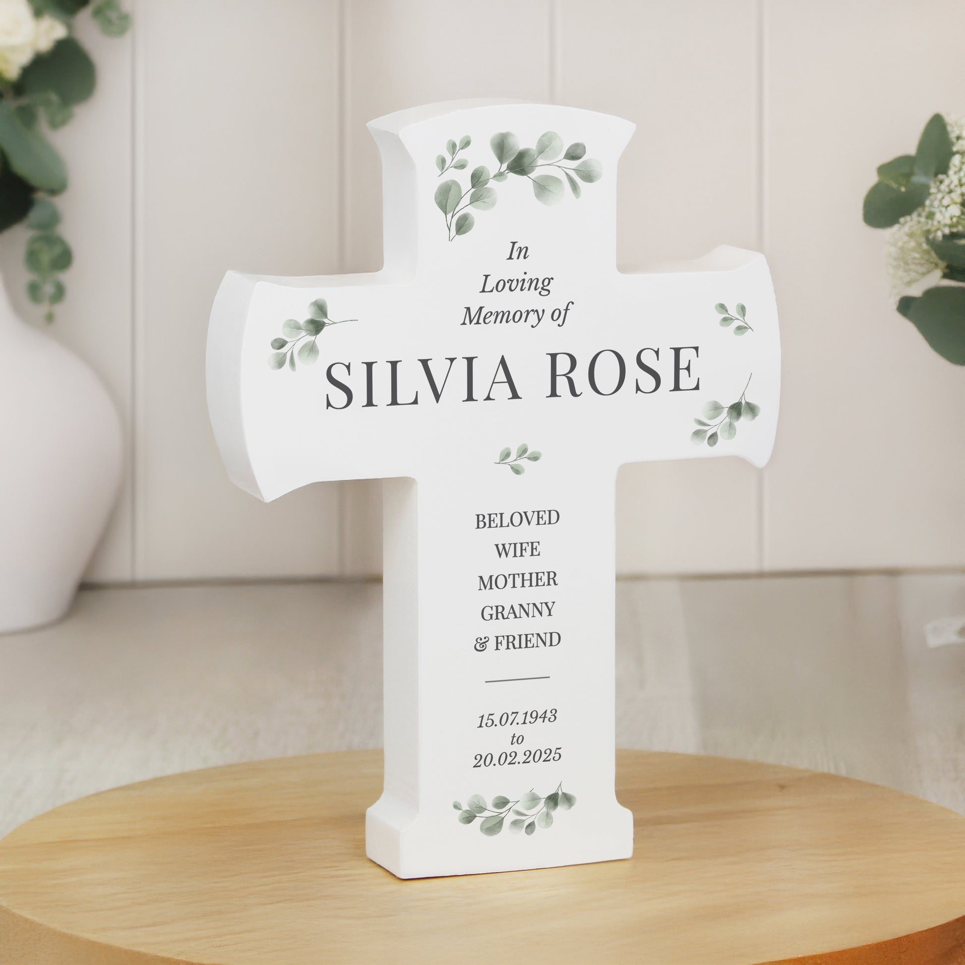 Memorial cross for Silvia Rose on a wooden surface with decorative elements.