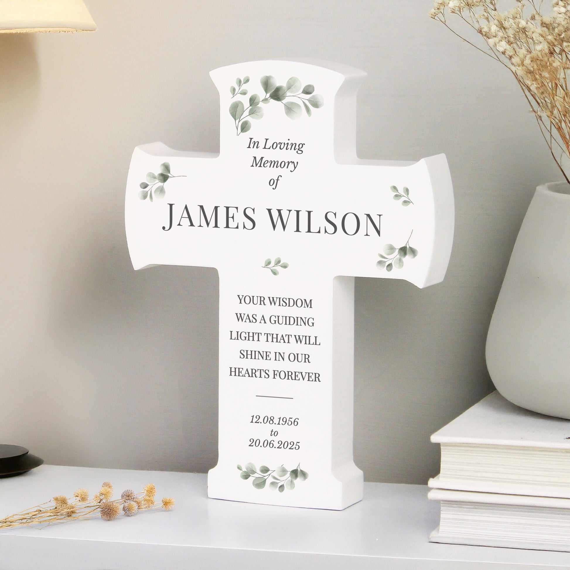 Memorial cross for James Wilson on a shelf with decorative elements.