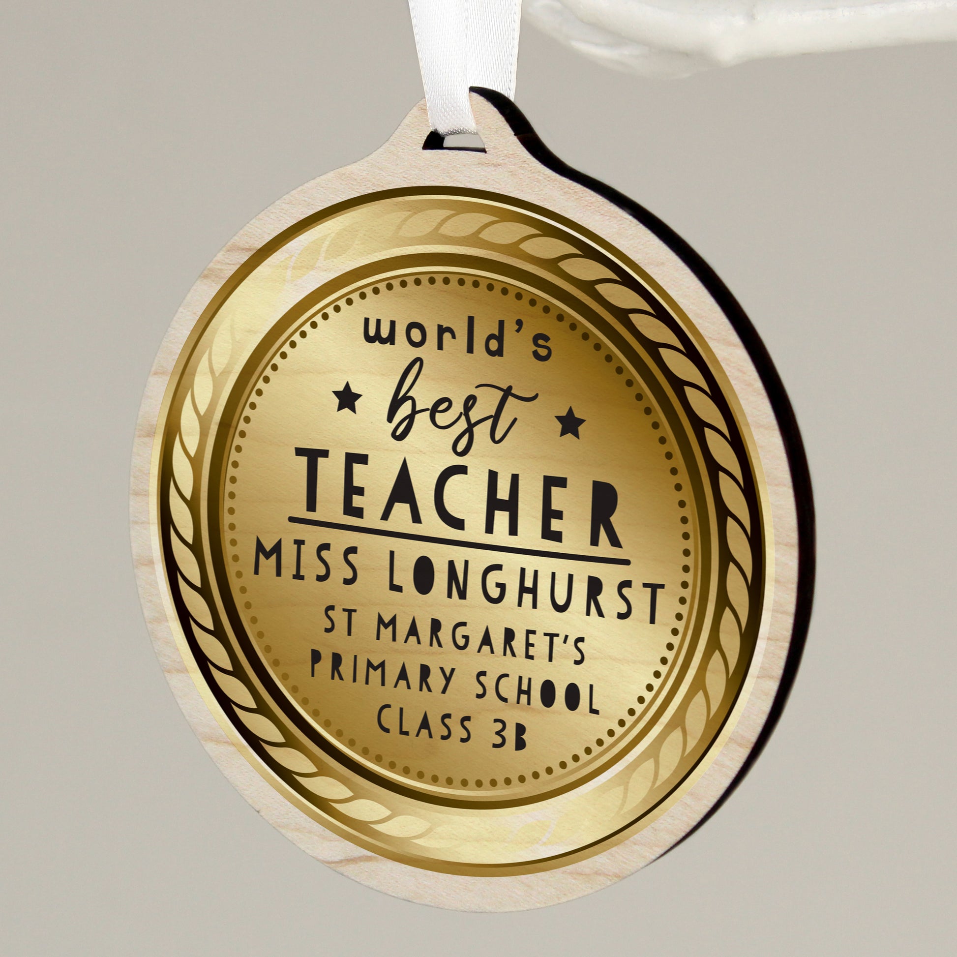 Gold coloured medal with 'World's Best Teacher' engraving on a grey background
