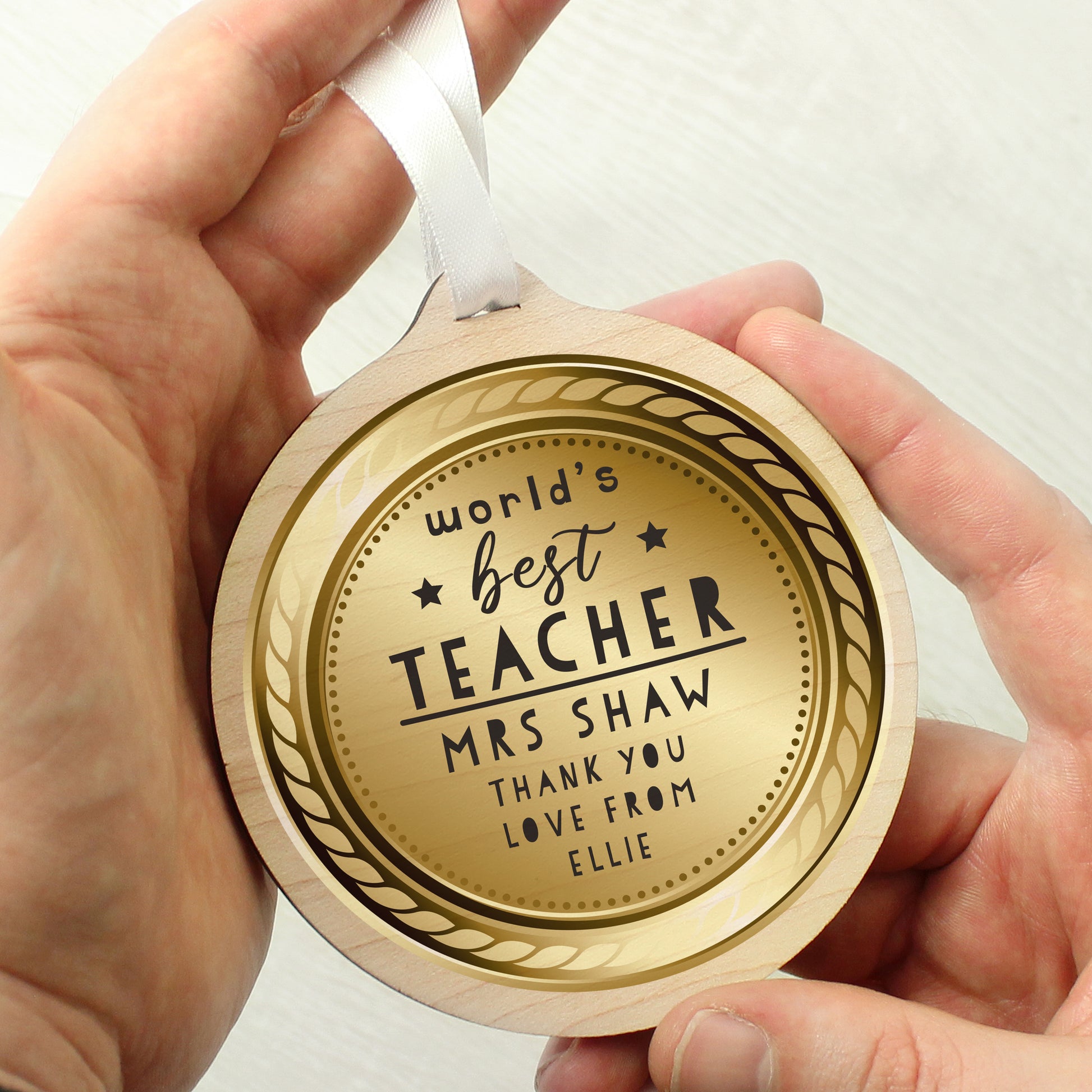 Hand holding a wooden round plaque with engraved text on a white background