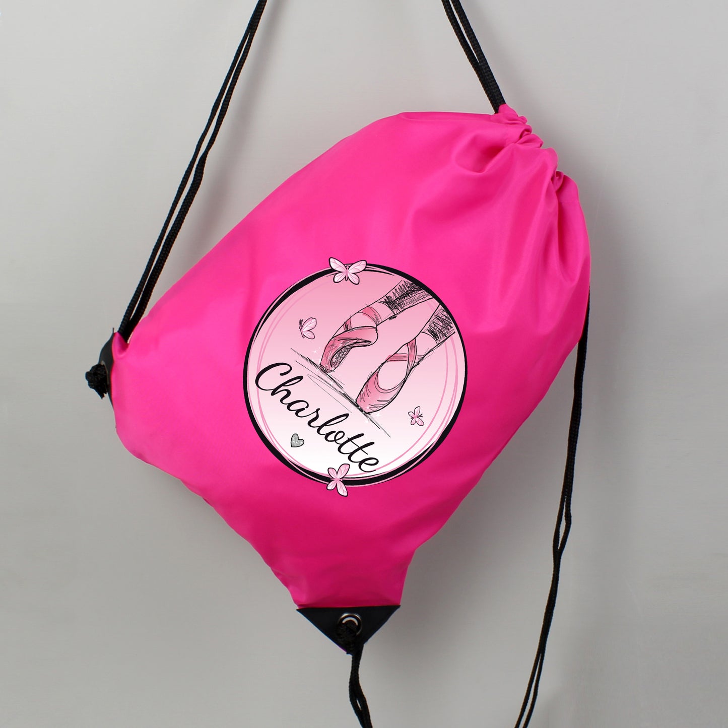 Pink drawstring bag with ballet-themed design and 'Charlotte' text on a gray background