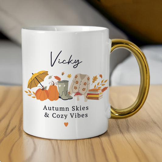 White mug with autumn-themed design and 'Vicky' printed on it, featuring pumpkins, boots, and an umbrella.