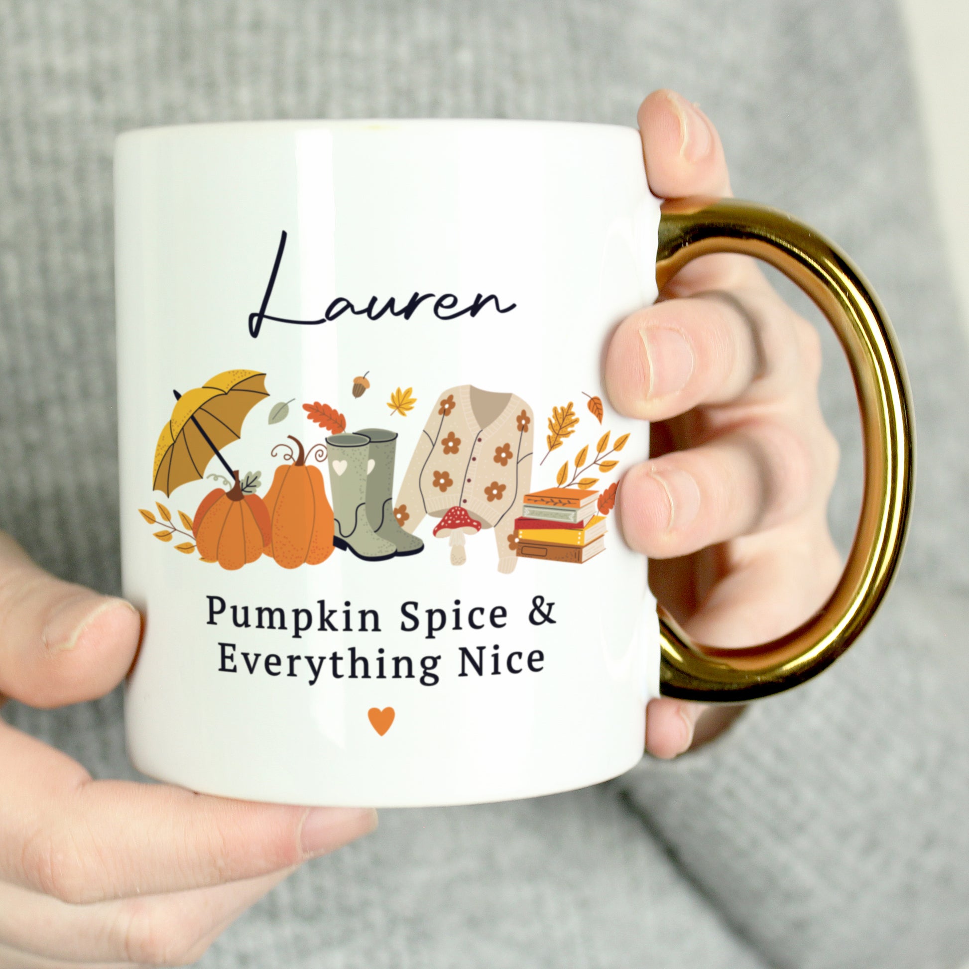 Person holding a white mug with autumn-themed design and text