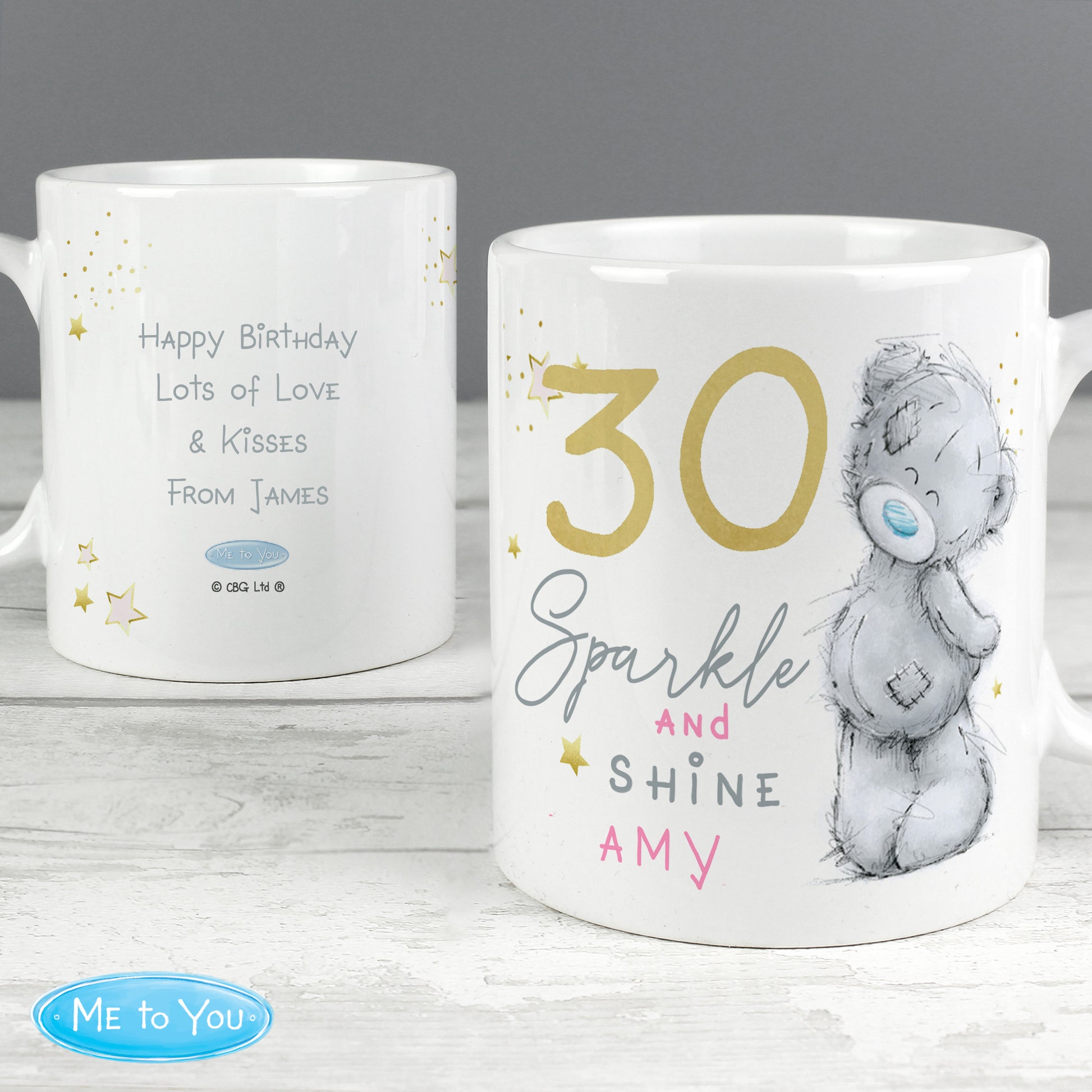 Back and front of personalised mugs with text and a bear illustration on a wooden surface.