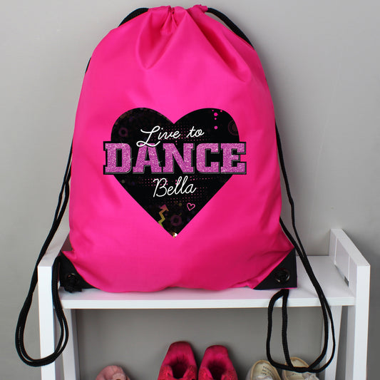 Pink drawstring bag with 'Live to Dance Bella' design on a white shelf.
