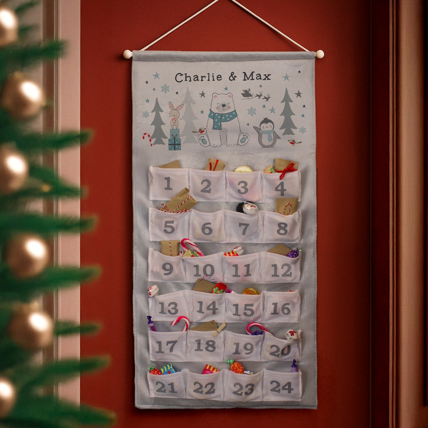 Hanging advent calendar with Charlie & Max text by a Christmas tree.