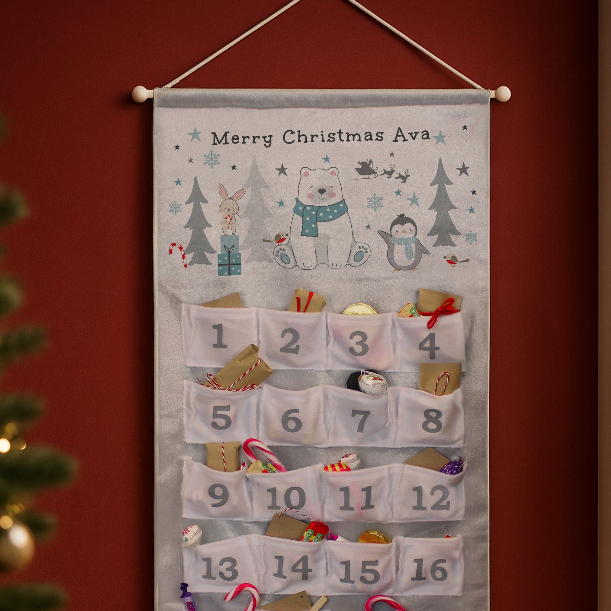 Festive Advent calendar with cartoon characters and numbered pockets on a red wall.