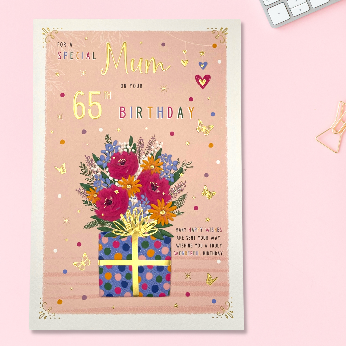 Image of Mum 65th card showing brightly coloured gift and flowers with gold butterflies
