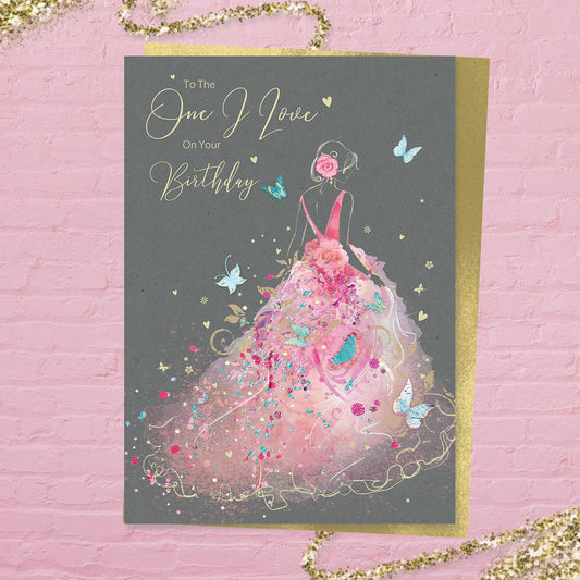 To The One I Love On Your Birthday' card from the 'Grace' range. Featuring a beautiful lady In a pink frothy, flowing dress. Added sparkle and gold foil detail. Printed insert with colour image and heartfelt verse. Complete with gold colour envelope