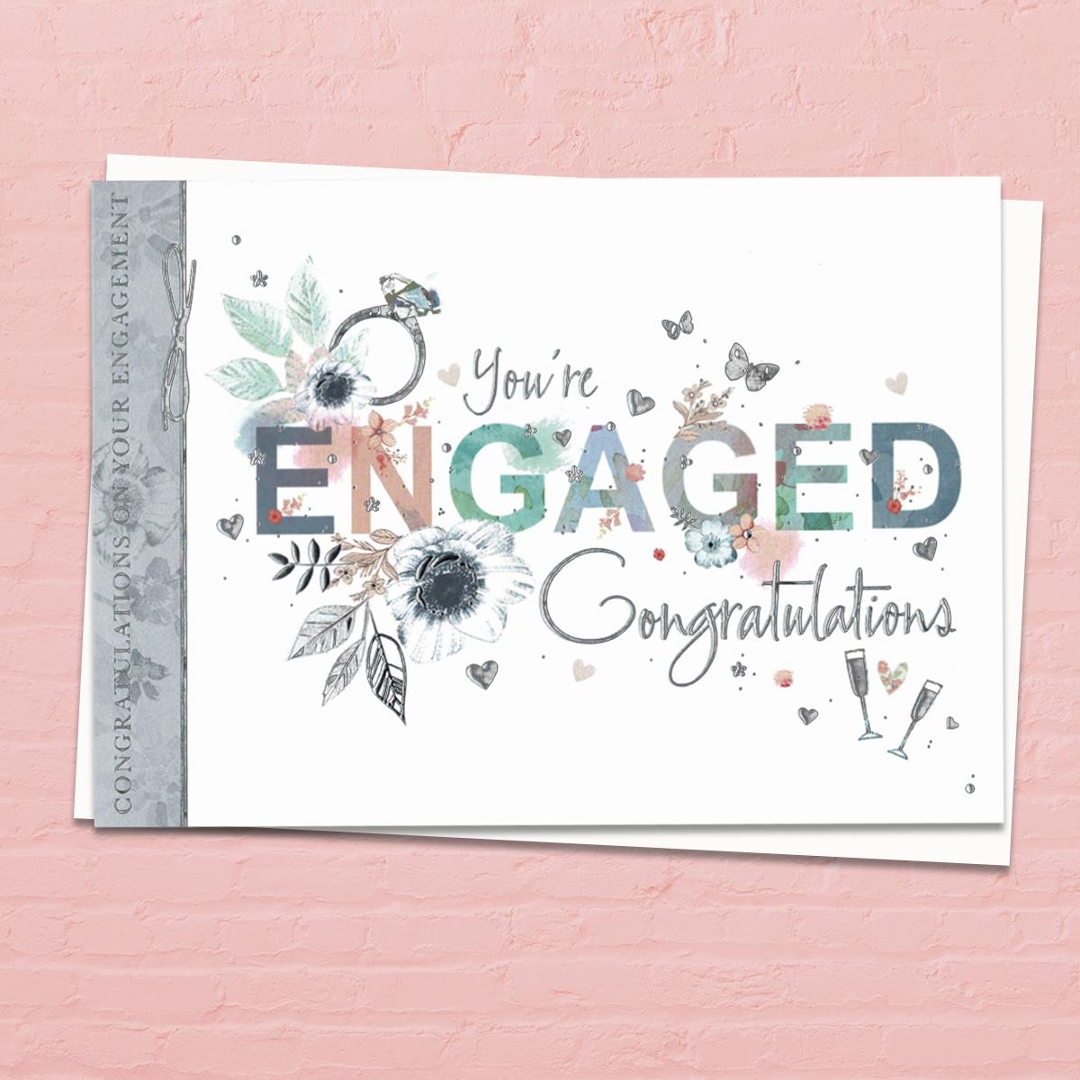 You're Engaged Congratulations' Card. This 'Landscape' Card Features A Diamond Ring with Beautiful Floral Adorned Letters Of 'Engagement' . With Beautiful Silver Foil Detail And White Envelope